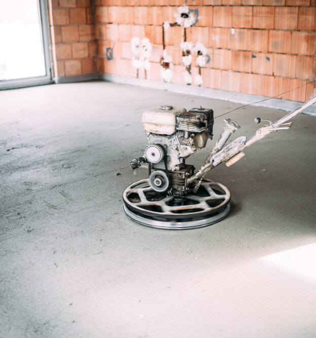 industrial worker finishes concrete screed with trowel machine